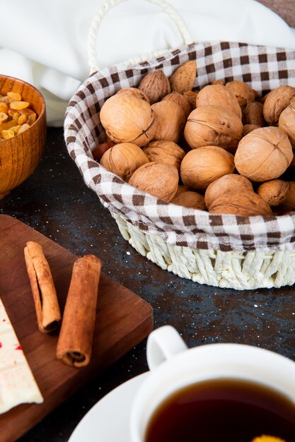 Side view of walnuts in a wicker basket and cinnamon sticks on rustic