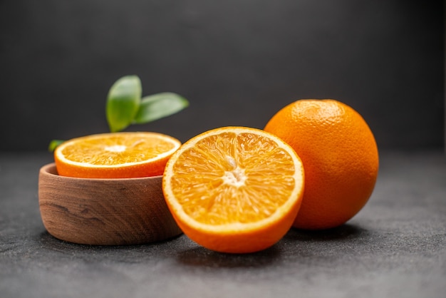 Side view of whole and cut fresh lemons with leaves on dark background