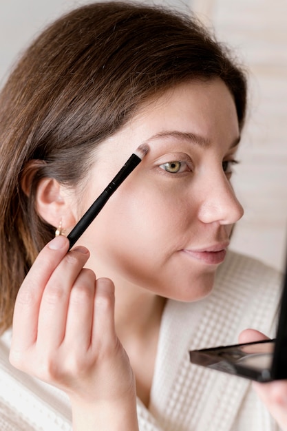 Free Photo side view woman applying eyeshadow