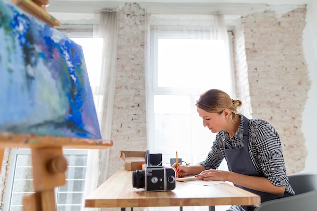 Free Photo side view of woman in apron working at desk