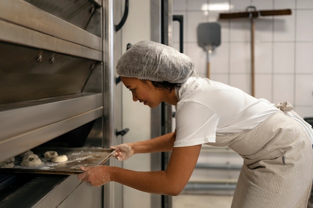 Free Photo side view woman baking in kitchen