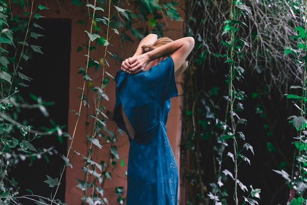 Free photo side view woman buttoning dress near old house