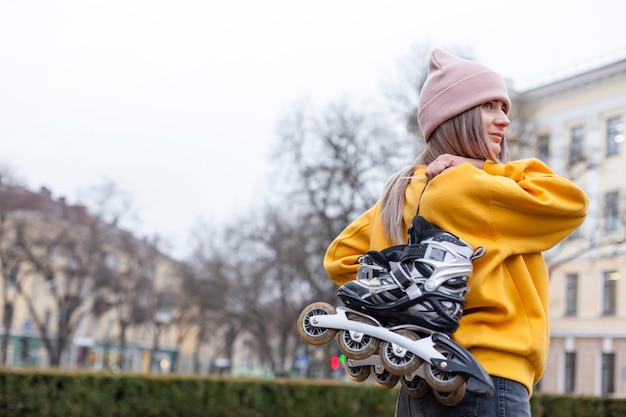 Free photo side view of woman carrying roller blades