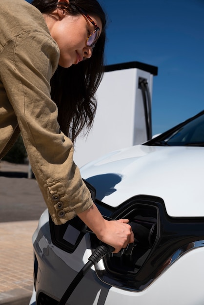 Free photo side view woman charging electric car