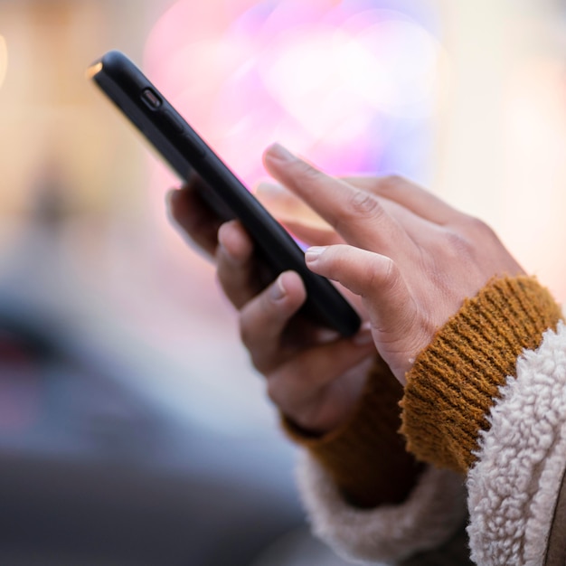 Free photo side view woman checking her phone outdoors