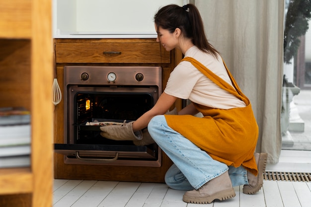 Free photo side view woman cooking pizza