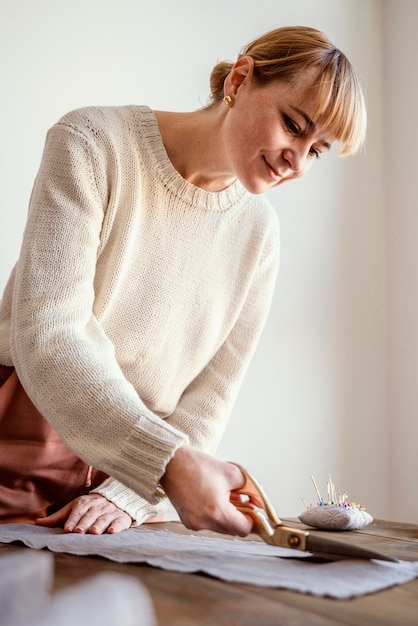 Free Photo side view woman cutting a fabric