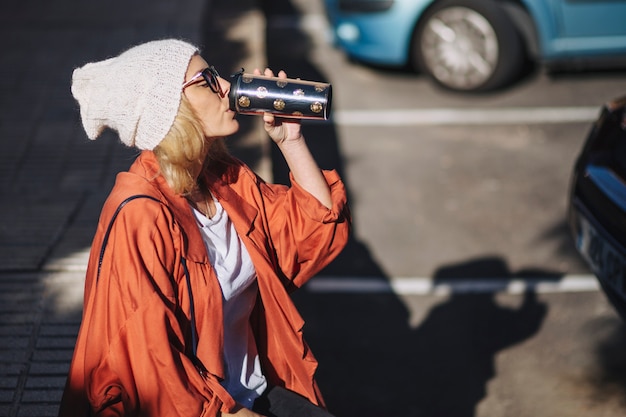 Free photo side view woman drinking on parking lot