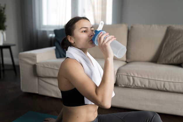 Side view of woman drinking water after exercising