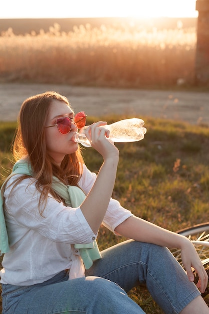 Side view of woman drinking water in the sunset