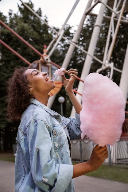 Free Photo side view woman eating cotton candy