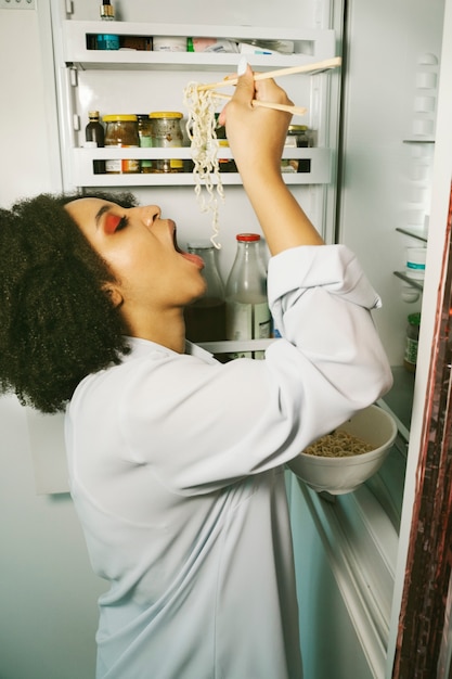 Free photo side view woman eating noodles