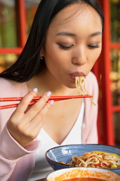 Free Photo side view woman eating tasty noodles