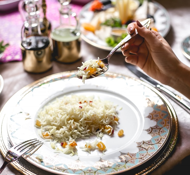 Side view woman eats boiled rice with raisins