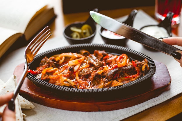 Side view a woman eats meat fajitos in a pan