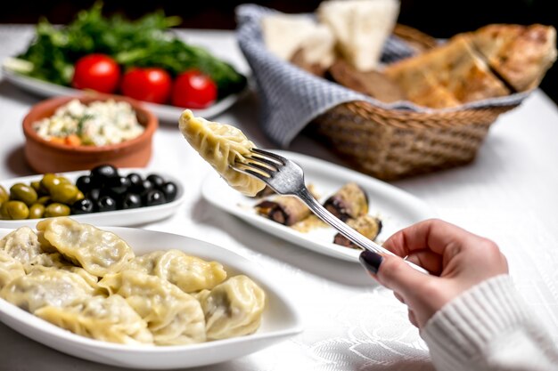 Side view woman eats traditional azerbaijani dish gyurza with olives