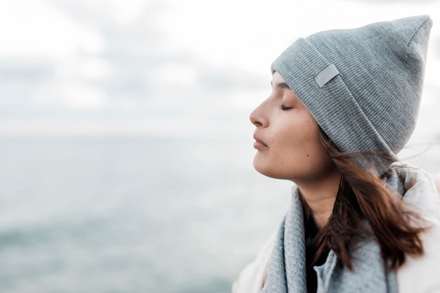 Free photo side view of woman enjoying the ocean breeze with copy space