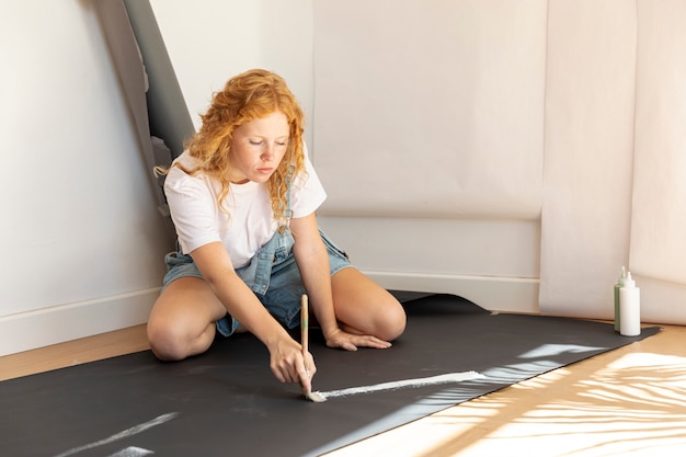 Free photo side view woman on the floor painting