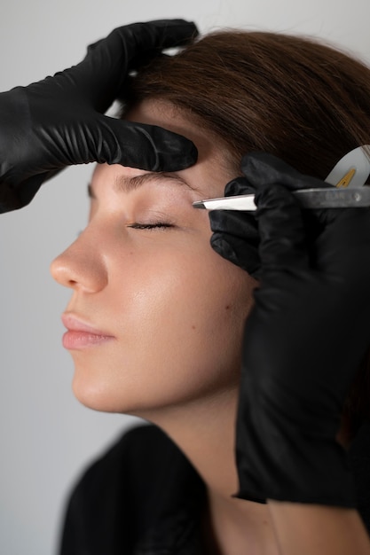 Free photo side view of woman getting her eyebrows done