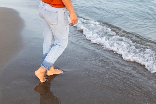 Free photo side view of woman getting her feet into the water at the beach