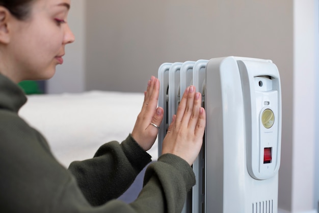 Side view woman getting warm near heater