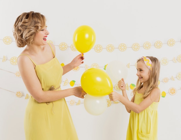 Side view of woman and girl posing with balloons and smiling