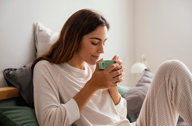 Side view of woman having coffee in bed