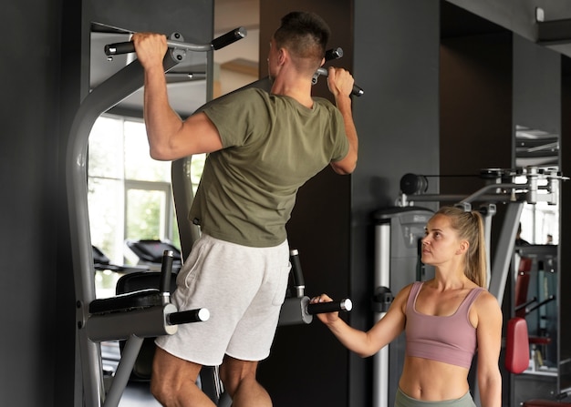 Side view woman helping man at gym