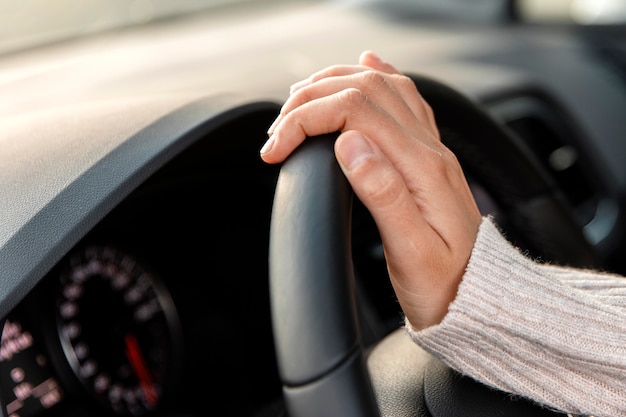 Free photo side view of woman in her car holding steering wheel while driving