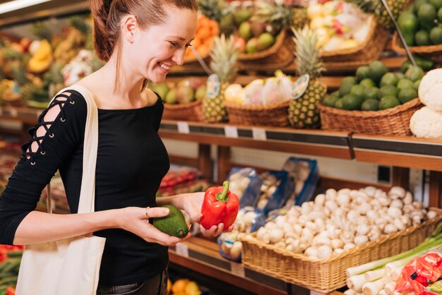 Side view woman holding avocado and bell pepper