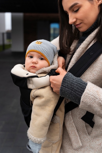 Side view woman holding baby in carrier