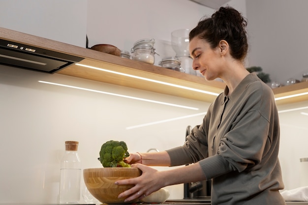 Free photo side view woman holding broccoli