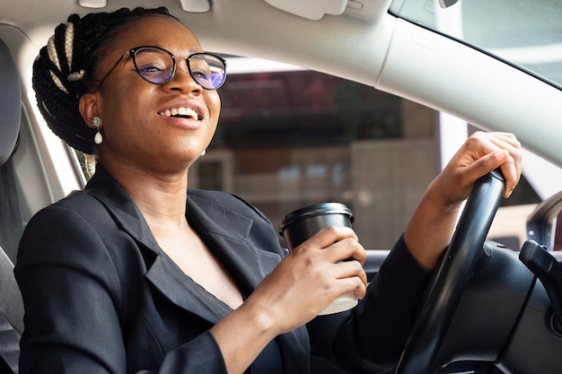 Side view of woman holding coffee cup while in her car