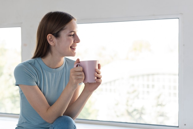 Free photo side view woman holding a cup of coffee