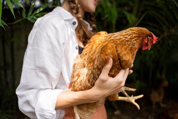 Free photo side view woman holding hen