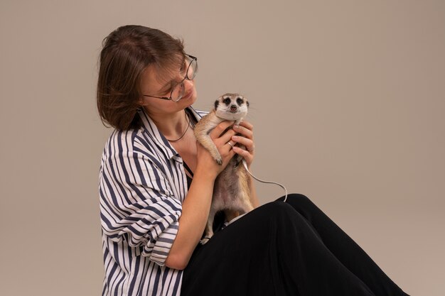 Side view woman holding meerkat