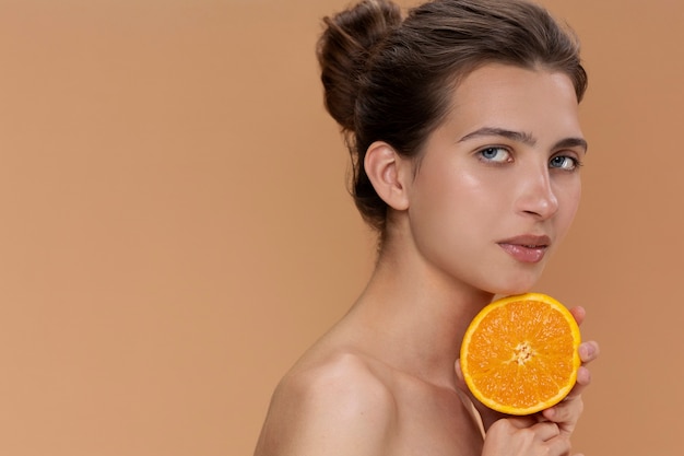 Side view woman holding orange half