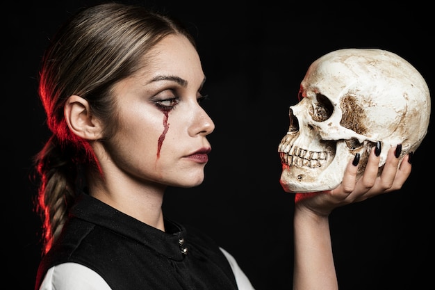 Free photo side view of woman holding skull