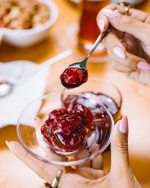 Side view of a woman holding a small saucer with strawberry jam