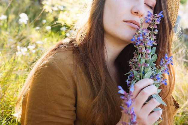 Free Photo side view of woman holding and smelling bouquet of flowers