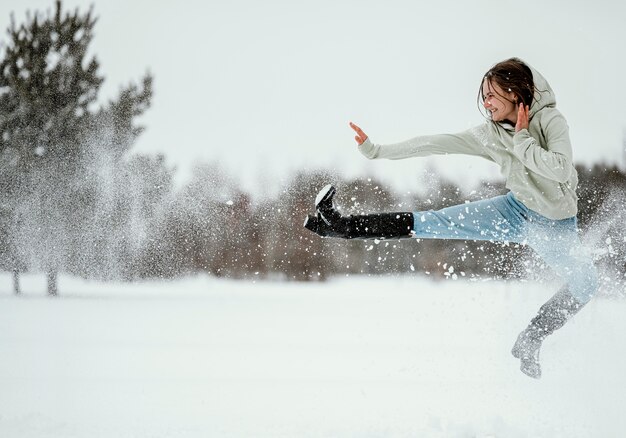 Side view of woman jumping outdoors in winter