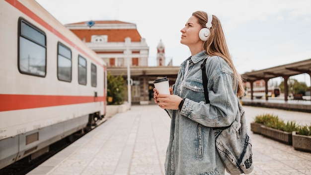 Side view woman listening to music at the train platform