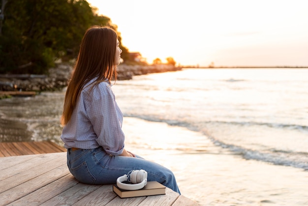 Side view woman looking at the sea at sunset