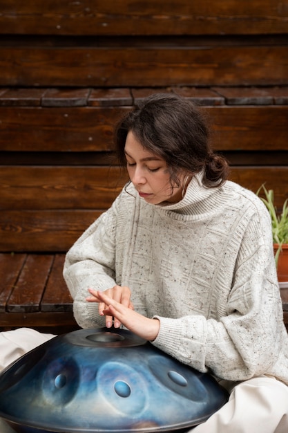 Free Photo side view woman making music with handpan