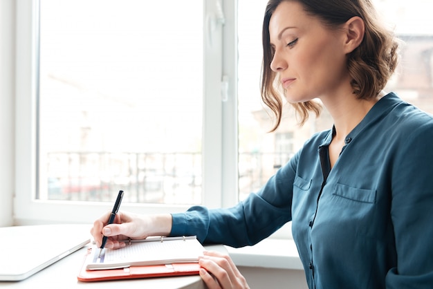 Free photo side view of a woman making notes in her diary