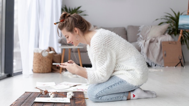 Side view woman making a vlog of her paintings at home