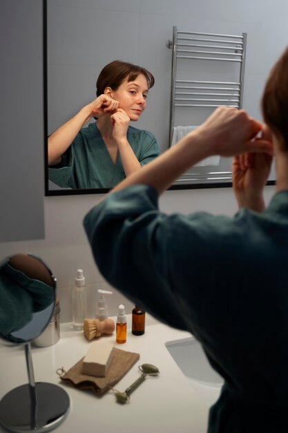 Side view woman massaging face in bathroom