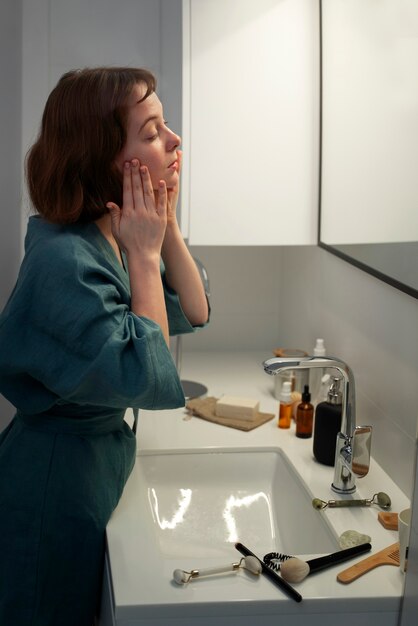 Side view woman massaging face at home