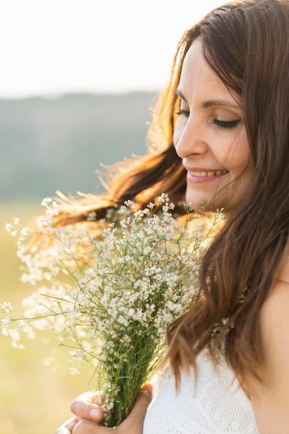 Free Photo side view of woman in nature with bouquet of flowers