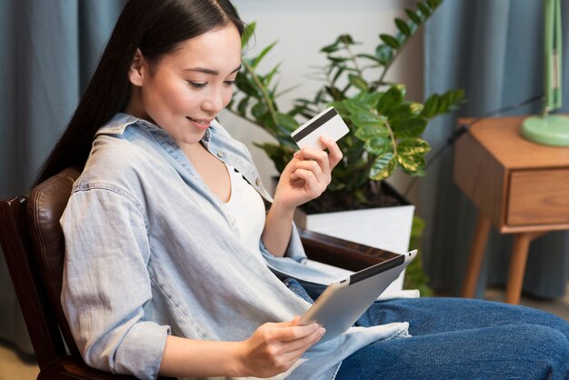 Side view of woman ordering online using tablet and credit card